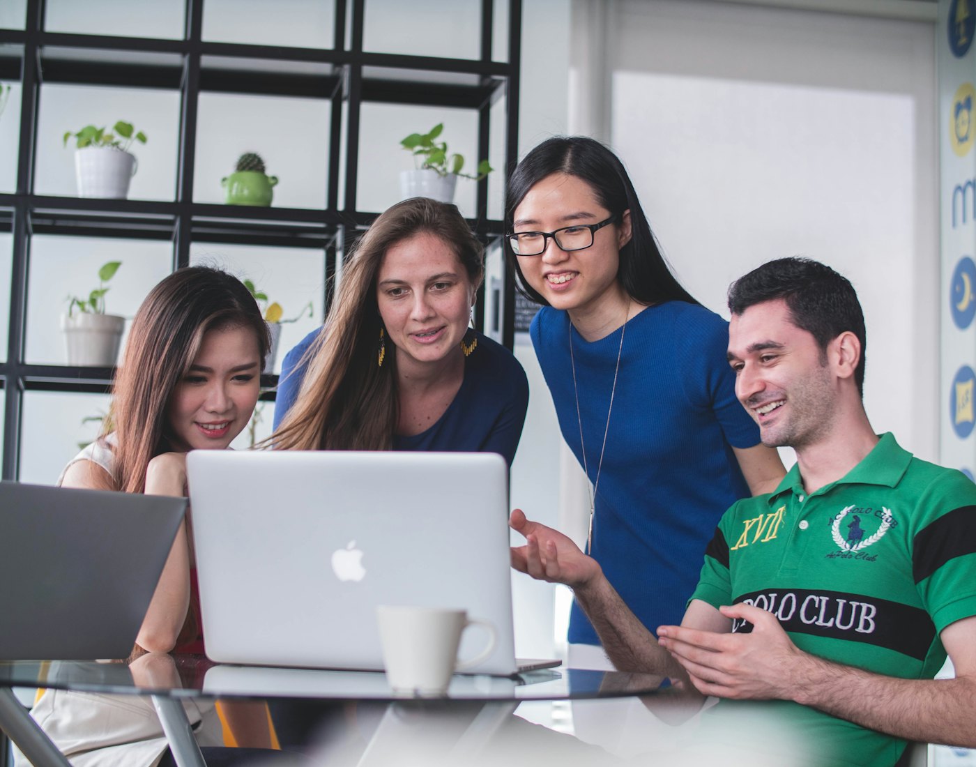Students smiling as they work together around a laptop